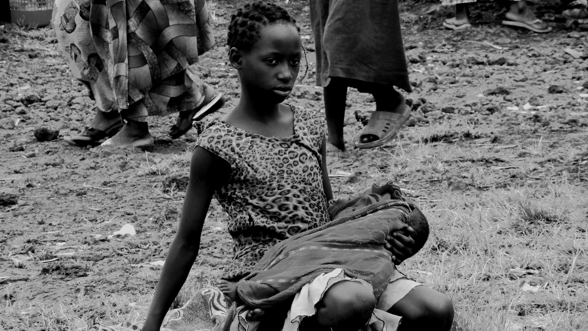Une jeune fille porte un bébé sur ses genoux en attente d'une ration alimentaire du PAM à Mugunga crédit photo : Ley Uwera 